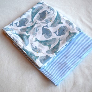May include: Two fabric baby blankets, one with a white background and blue whale print, and the other with a blue and white striped pattern.