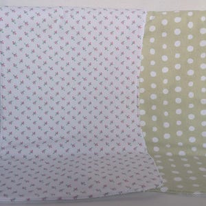 Pode incluir: Duas mantas de beb&eacute; drapeadas sobre uma cadeira branca. Uma &eacute; branca com um pequeno padr&atilde;o floral rosa. A outra &eacute; verde claro com grandes bolinhas brancas. As mantas s&atilde;o macias e provavelmente de algod&atilde;o.
