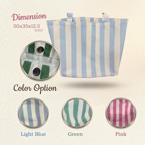 May include: A light blue and white striped tote bag with dimensions of 50 x 35 x 12.5 cm. The bag has two small handles and a close-up of the fabric shows two black buttons. Color options include light blue, green, and pink.