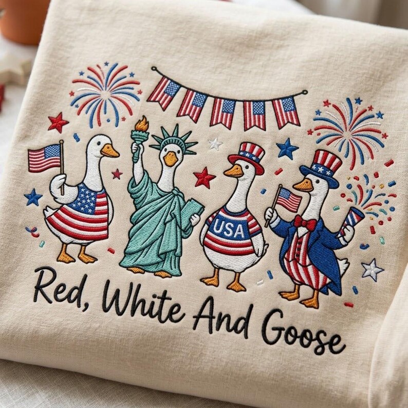 May include: Cream-colored sweatshirt with an embroidered design featuring geese dressed in patriotic attire. The geese are depicted as the Statue of Liberty and holding flags, with fireworks and the text "Red, White And Goose".