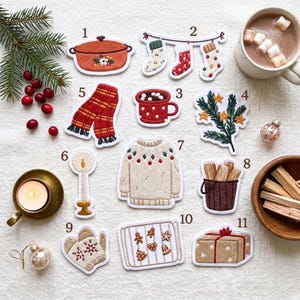 Puede incluir: Una colección de once parches bordados con temas navideños: una olla, calcetines, una taza, una rama de pino, una bufanda, una vela, un suéter, un cubo de madera, manoplas, una bandeja de horno con galletas y un regalo, numerados del uno al once.