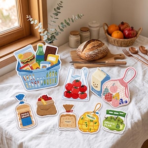 May include: A collection of flat, illustrated food-themed magnets or stickers featuring a blue shopping basket filled with groceries, a bag of tomatoes, a milk carton, a mesh bag of fruit, bread, and various produce items labeled organic.