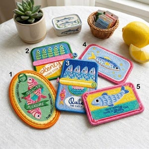 May include: Five embroidered patches featuring fish-themed designs and text. Patch 1 is oval with pink fish and green banners. Patches 2, 3, 4, and 5 are rectangular with various fish illustrations, blue, yellow, and pink colors, and witty fish-related text.
