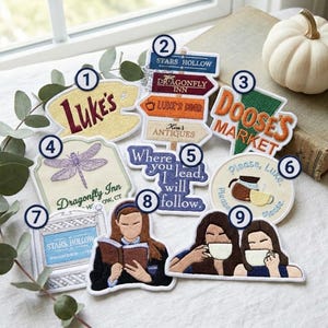 May include: A collection of nine embroidered fabric patches featuring designs inspired by a television show. The patches include text such as Luke's, Stars Hollow, Dragonfly Inn, Doose's Market, and Where you lead, I will follow, alongside illustrations of coffee cups, a dragonfly, and two figures.