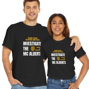 May include: Two people wearing black t-shirts with white text that reads "DEMAND JUSTICE FOR OFFICER JOHN 'KEEFE INVESTIGATE THE MC ALBERTS". The text is overlaid with a gold star.