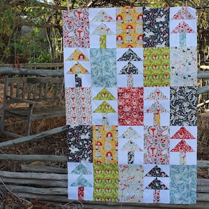 May include: A quilt with a patchwork design featuring a repeating pattern of stylized trees in various colors, including red, green, yellow, and blue. The trees are arranged in a grid pattern on a white background.