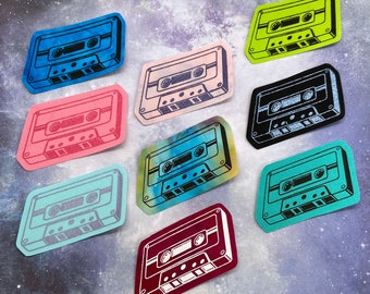 May include: Ten colorful cassette tape stickers with a retro design. Each sticker features a different color and design, including blue, pink, green, purple, and black.