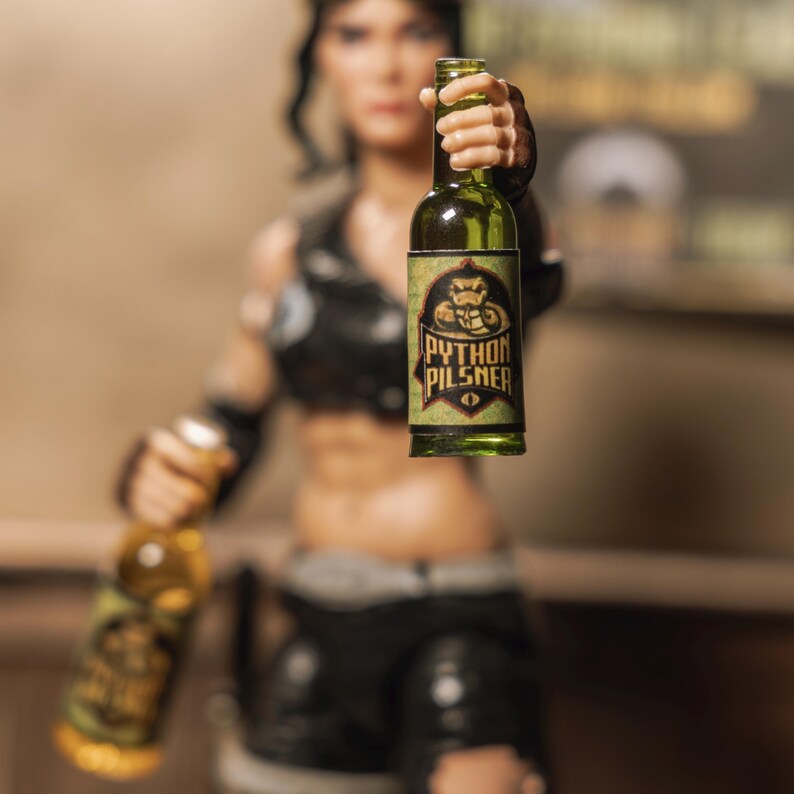 May include: A green glass bottle with a label that says "Python Pilsner" and a graphic of a snake. The bottle is being held by a person's hand.