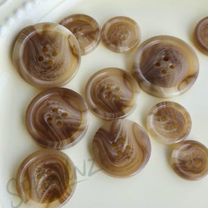 Ljusbruna knappar i harts, finns i flera storlekar. Lämpliga för klädaccessoarer, dockdekorationer och gör-det-själv-projekt.