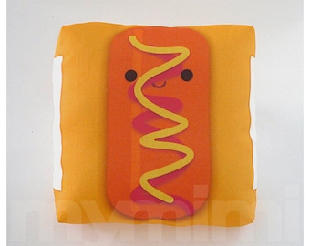 May include: A yellow and orange plush pillow shaped like a hot dog with a smiling face and a squiggly line of yellow mustard.