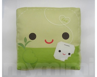 May include: Green and white plush pillow shaped like a tea bag with a smiling face and the word "tea" in a heart.