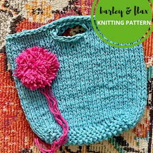 Könnte beinhalten: Eine blaue gestrickte Tragetasche mit einem rosa Bommel. Die Tasche hat einen Henkel und ist aus einem dicken Garn gefertigt. Der Text "barley & flax knitting pattern" ist auf dem Bild zu sehen.