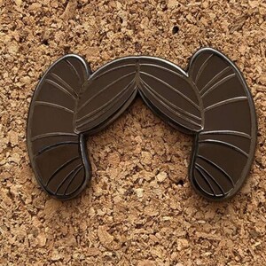 May include: Black metal pin shaped like Princess Leia's hair buns.