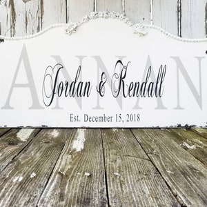 Puede incluir: Un letrero de madera blanco con un acabado desgastado, con los nombres "Jordan & Kendall" en una fuente cursiva, con el texto "Est. December 15, 2018" debajo.