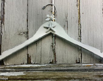 May include: White wooden hanger with a white starfish and a white bow on the top.