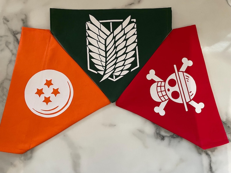 May include: Three triangular bandanas in orange, green, and red. The orange bandana features a white circle with four stars. The green bandana has a white emblem. The red bandana displays a white skull and crossbones design.
