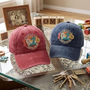 May include: A red and a blue baseball cap, each featuring a circular embroidered patch on the front. The patch displays a sunset graphic with the text "VINTAGE 1976 LIMITED EDITION" in a retro font. Both caps have a distressed, washed-out fabric finish.