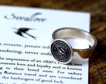 May include: A silver ring with a swallow design. The ring is handcrafted using the impression of an 1830's wax seal. The text on the card reads: "Toujours errante, jamais infinie {Always wandering, never unfa...Handcrafted using the impression of an 1830's rich wax seal, the swallow represents love and loyalty and is known for always returning to their loved ones. For sailors swallows signify long distance travel and are considered bearers of good news, the harbingers of good luck. PLUM & POSEY"