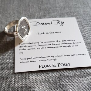 May include: Silver ring with a wax seal pendant featuring a telescope, stars, and a crescent moon. The card reads "Dream Big, Look to the stars" and includes a quote by Vincent Van Gogh: "For my part I know nothing with any certainty, but the sight of the stars makes me dream." The card is signed "Plum & Posey."