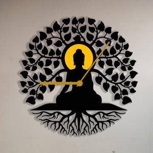 May include: A black metal wall clock featuring a silhouette of Buddha meditating within a tree with roots. The clock is hanging on a white wall in a living room setting with a green sofa and yellow throw pillows.
