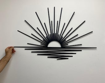 May include: Black metal wall art depicting a stylized sunset with sun rays and a horizon line.