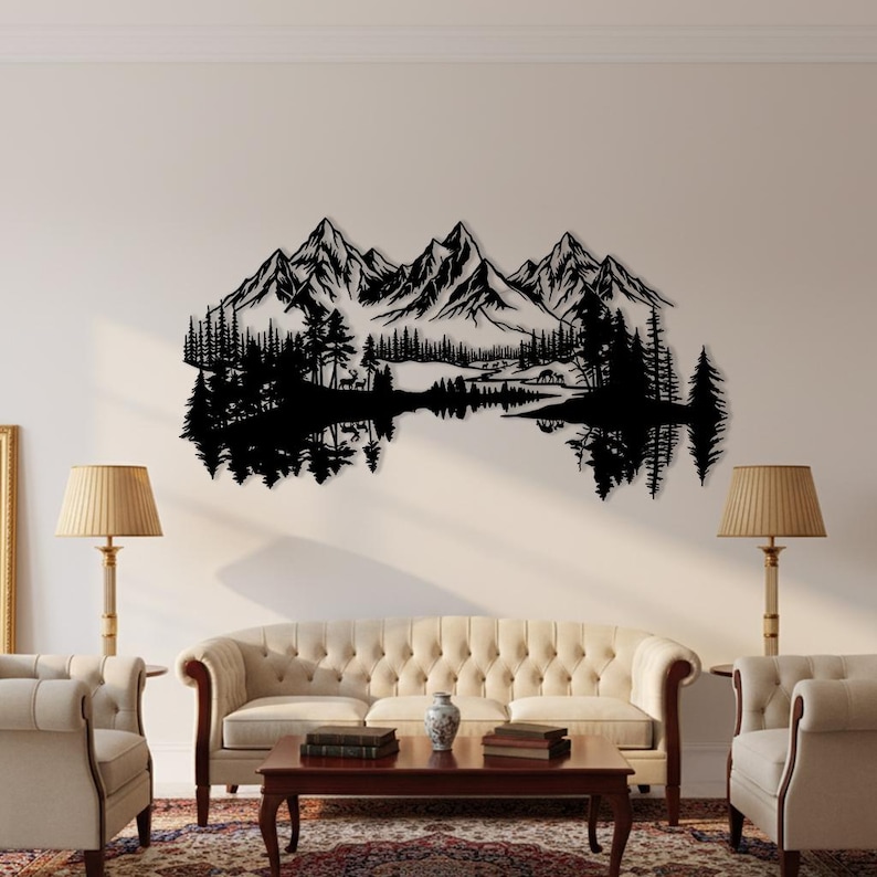 May include: Black metal wall art depicting a mountain range, trees, and a lake with reflections. The artwork is mounted on a white wall above a sofa and chairs. The scene includes a detailed silhouette of a natural landscape.