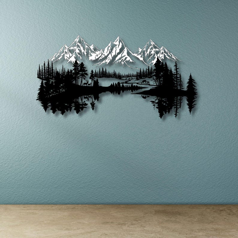 May include: Black metal wall art depicting a mountain range with snow-capped peaks, a forest, and a lake. The artwork features a mirrored reflection of the forest and mountains in the lake. The art piece is mounted on a blue wall.