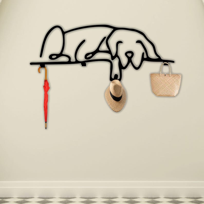 May include: Black metal wall hook shaped like a sleeping dog with a red umbrella, a straw hat, and a woven basket hanging from it.