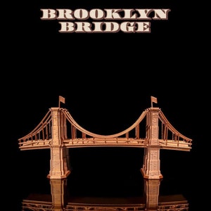 Könnte beinhalten: Ein Miniaturmodell der Brooklyn Bridge aus Holz, in brauner Farbe lackiert. Die Brücke ist über einer schwarzen Oberfläche aufgehängt, mit einer darunter sichtbaren Spiegelung der Brücke.