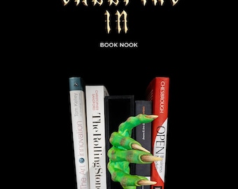 May include: A green monster hand bookend with long claws holding up a stack of books. The books have titles like "The Rolling Stones" and "Open Business World". The bookend is on a black surface with a black background. The text "CREEPING In BOOK NOOK" is at the top of the image.