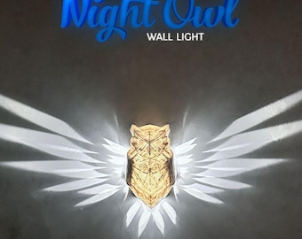 May include: A gold owl-shaped wall light with geometric details casts a shadow of wings on the wall. The light is labeled "Night Owl Wall Light".