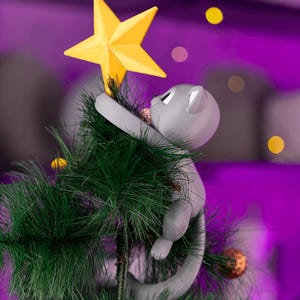 May include: A gray cat Christmas tree topper reaching for a yellow star. The cat is climbing a green artificial Christmas tree. The background is a blurred purple with yellow and orange bokeh lights.