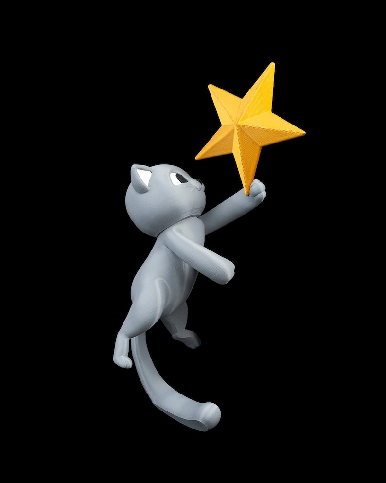May include: A gray cat figurine reaching for a bright yellow star. The cat is in a playful pose, with its tail curved and its eyes focused on the star. The background is solid black.