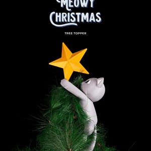 May include: A gray cat-shaped Christmas tree topper holding a yellow star. The cat is climbing a green artificial Christmas tree. The words "Meowy Christmas" and "Tree Topper" are written in white and blue on a black background.
