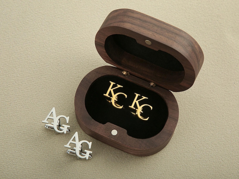 A pair of gold cufflinks inside a brown wooden case with a pair of silver cufflinks outside
