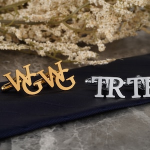 May include: Two pairs of cufflinks, one gold and one silver. The gold cufflinks spell out "WGWG" and the silver cufflinks spell out "TRTR".