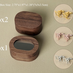 May include: Two oval wooden boxes with lids, one with a mirror inside. The boxes are labeled "Box 1" and "Box 2". Three pairs of cufflinks are shown in separate boxes: gold, rose gold, and silver.