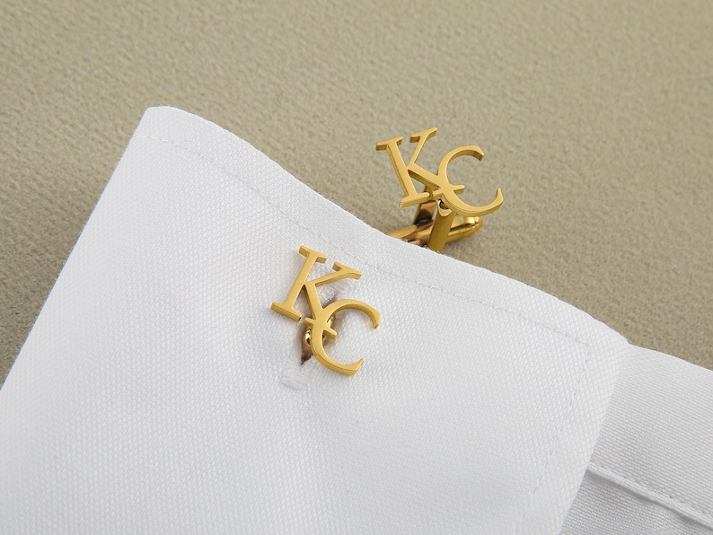 May include: A pair of gold cufflinks with the letters "KC" engraved on them.