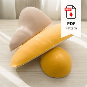 以下が含まれることがあります： ベージュ、黄色、黄橙色の柔らかい布の3つの形。形状には、丸みを帯びた形状、長く湾曲した形状、半円が含まれます。「PDF Pattern」というテキストが入った白いバナーが右上隅にあります。