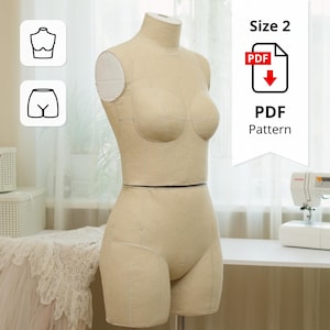 Puede incluir: Maniquí de costura beige con forma de busto y cadera, diseñado para coser y crear patrones. El maniquí está marcado con líneas de cuadrícula y tiene una etiqueta de talla 2. También se ve un icono de patrón PDF.