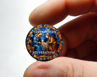 May include: A stained glass style round ornament featuring a depiction of the Holy Family, Mary, Joseph, and baby Jesus. The ornament is surrounded by a colorful border with the text "NIX CREATIONS" at the top and bottom.