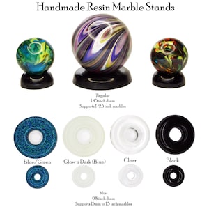 May include: Handmade resin marble stands in various colors and designs. The image shows three marbles on black stands, with a variety of stand options, including blue/green, glow-in-the-dark, clear, and black. The text indicates sizes.