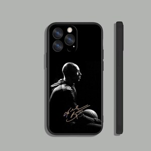 May include: Black and white phone case with a silhouette of a basketball player holding a basketball. The player's signature is in gold lettering.