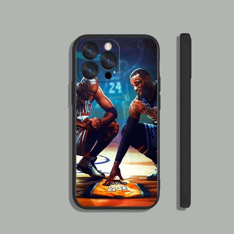 May include: A black phone case with a photo of Michael Jordan and LeBron James on a basketball court. The case features a close-up of the two basketball players with their jerseys on. The case also features the number "24" on the court.