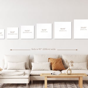 May include: A white sofa with brown throw pillows sits in front of a white wall with five different sized square canvases. The canvases are labeled with their dimensions in inches and centimeters. The text "Sofa is 90" (228cm) wide" is written below the canvases.