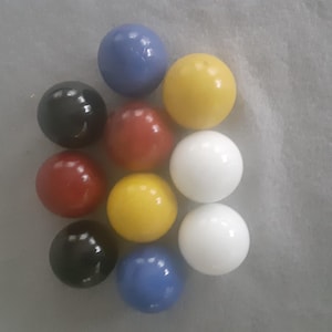Peut inclure: Une collection de neuf billes colorées de différentes couleurs, dont le noir, le rouge, le jaune, le blanc et le bleu. Les billes sont disposées les unes près des autres, créant un motif visuellement attrayant. Ces jouets classiques sont parfaits pour les jeux et la collection.