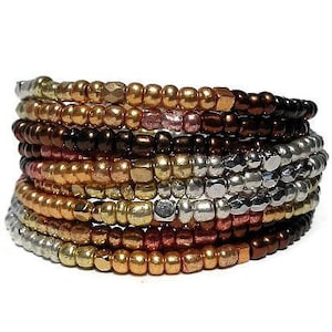 May include: A stack of 12 beaded bracelets in various shades of gold, copper, silver, and brown. The bracelets are made of small, round beads and are arranged in a graduated pattern.