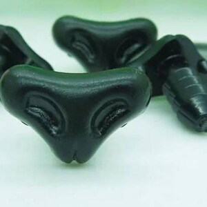 May include: Three black plastic toy eyes with a triangular shape and a raised design. The eyes have a small hole at the top for attaching.