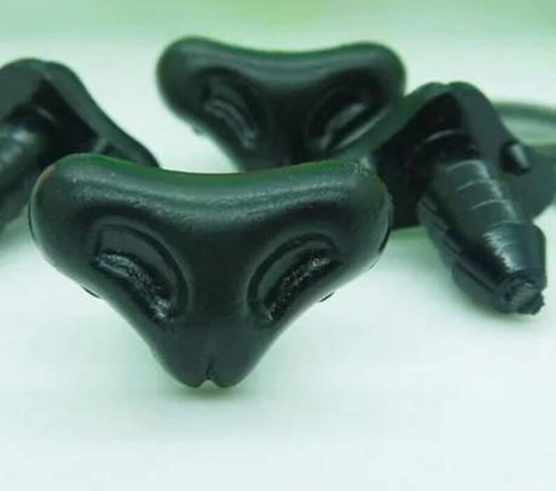 May include: Three black plastic toy eyes with a triangular shape and a raised design. The eyes have a small hole at the top for attaching.