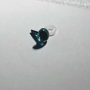 May include: A single green plastic safety eye with a black pupil and a white plastic washer.